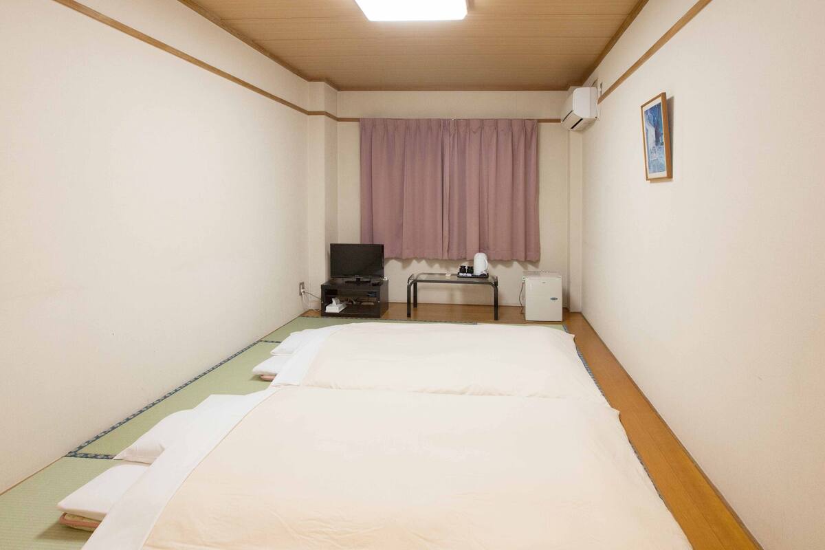 Une chambre d’hôtel avec un lit, un bureau, une télévision et une fenêtre avec des rideaux.