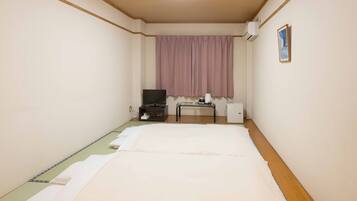A hotel room with a bed, a desk, a television, and a window with curtains.