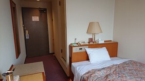 A hotel room with a bed, bedside table, lamp, and a door with a sign. - Hotel Castle Plaza Tagajo (Tagajo)
