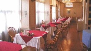 A dining area with tables covered in red tablecloths, wooden chairs, and a chandelier. - Hotel Amuse Tomioka (Tomioka)