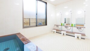 Un baño moderno con un ventanal grande, una bañera y un tocador con espejos y artículos de aseo.