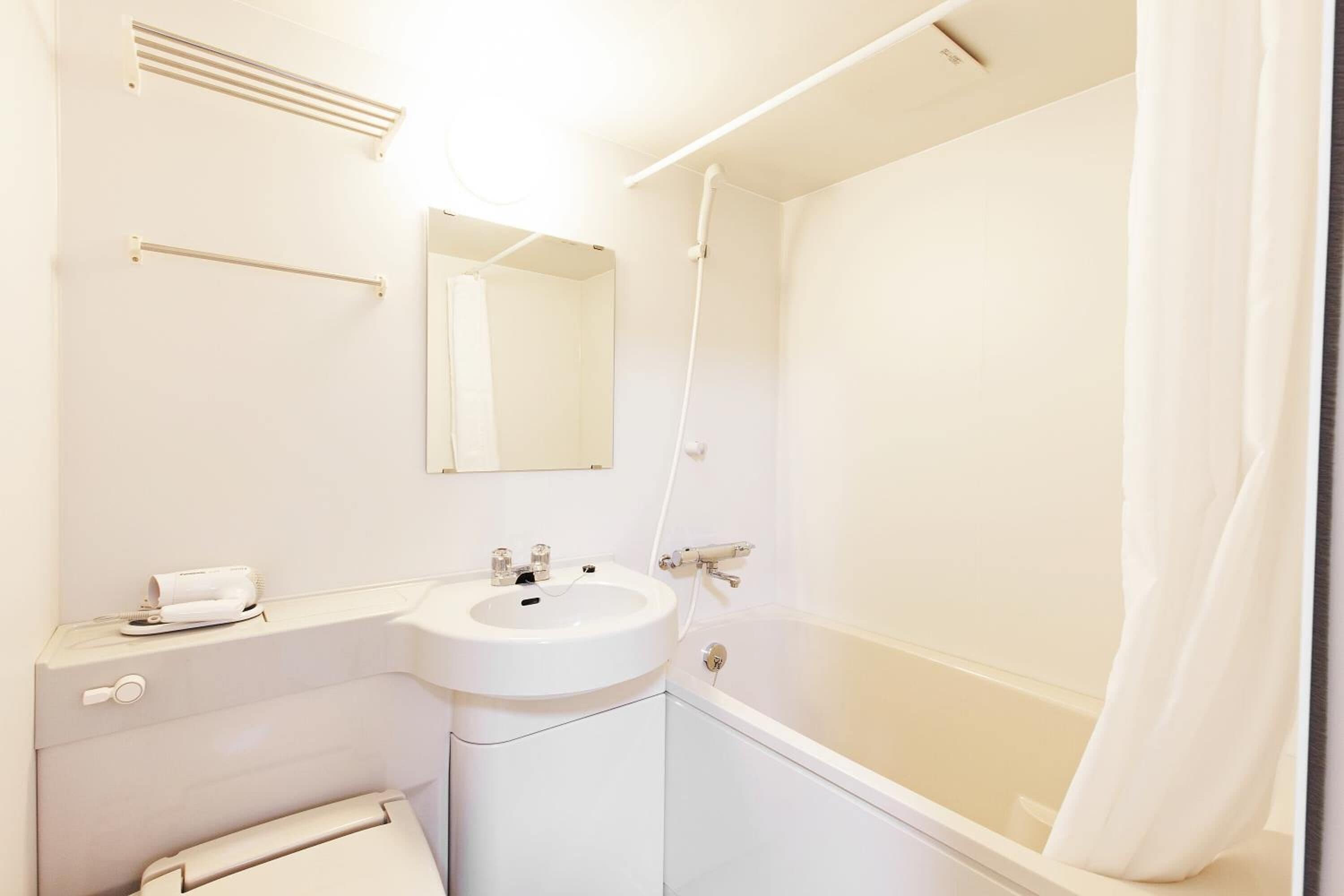 A bathroom with a white sink, mirror, and shower.