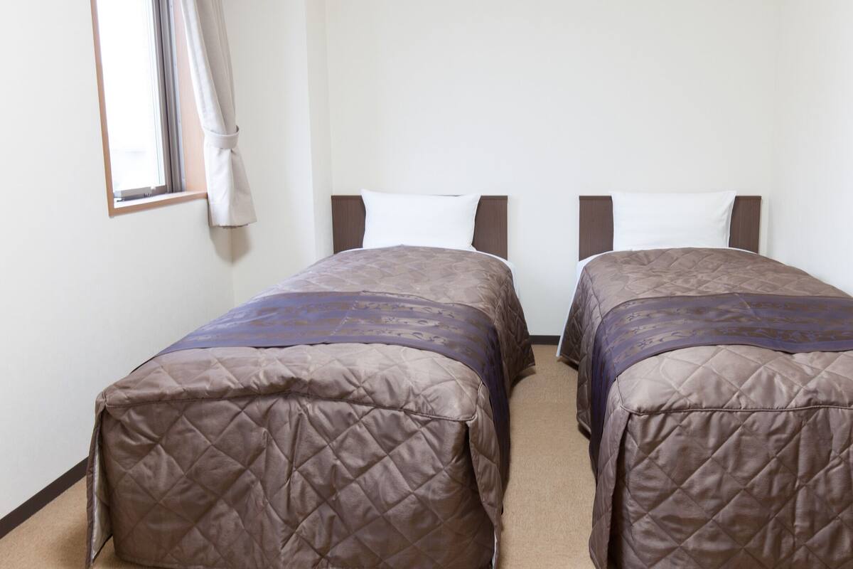 A room with two single beds, each with a quilted mattress and headboard.