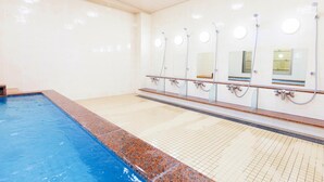 Una piscina con suelo de baldosas y borde de mármol.