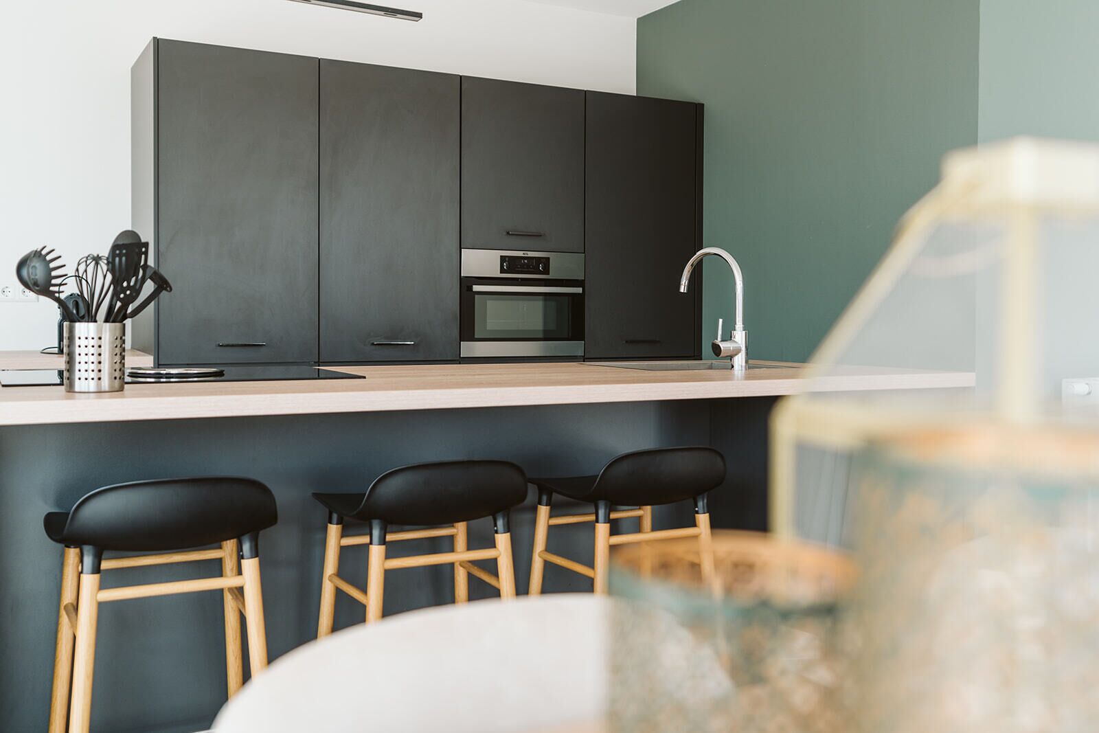 A modern kitchen with dark cabinets, a stainless steel oven, and a bar area with stools.