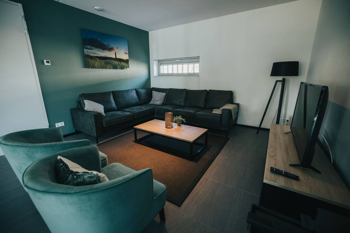 A modern living room with a sectional sofa, a coffee table, and a TV on a wooden stand.