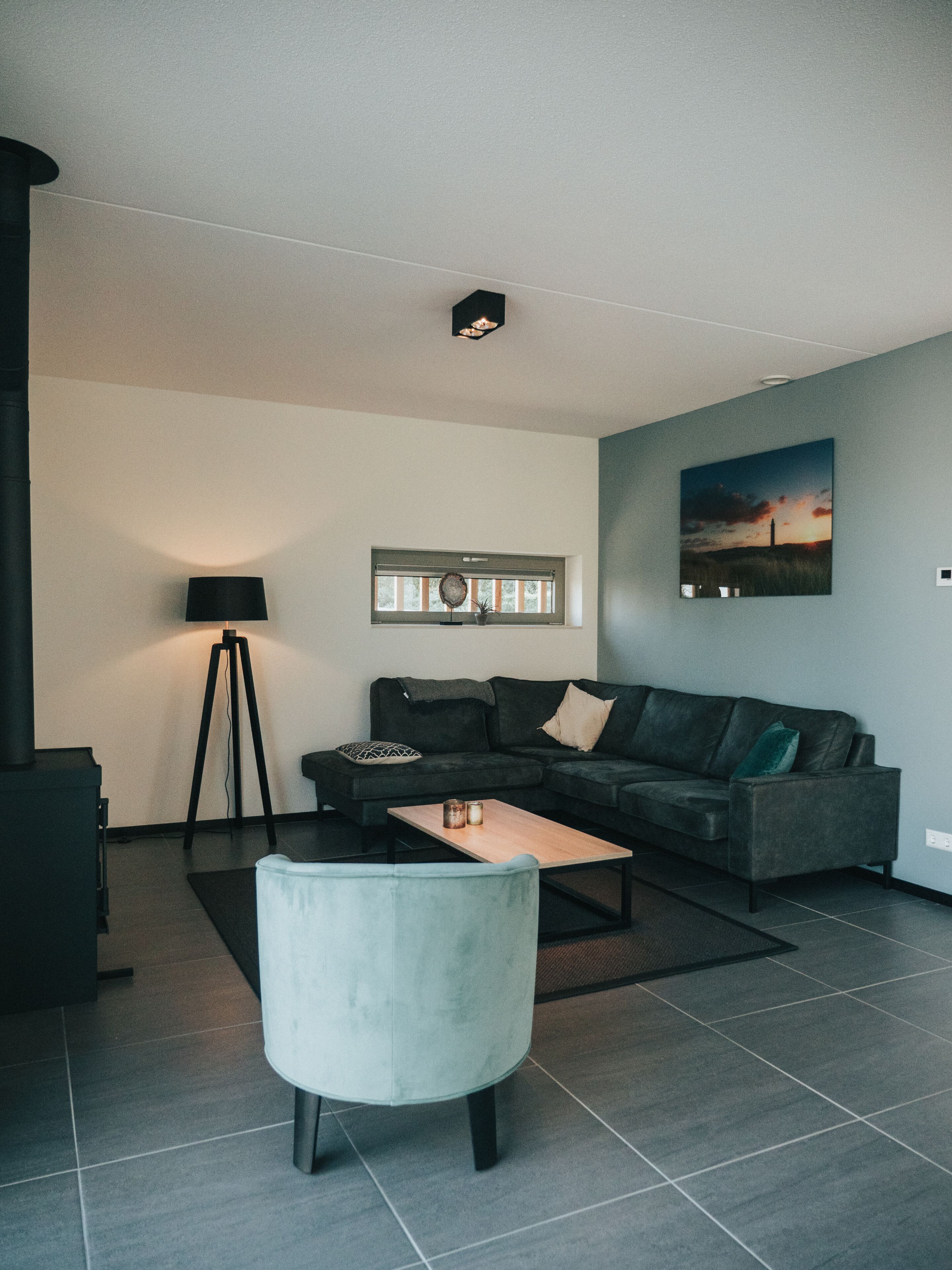 A modern living room with a sectional sofa, a coffee table, a floor lamp, and a painting on the wall.