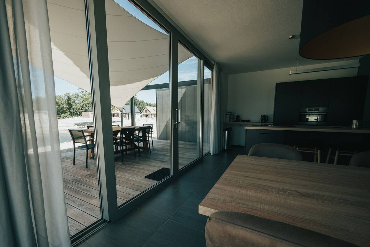 A modern kitchen with a built-in oven and microwave, a dining area with a table and chairs, and a sliding glass door leading to an outdoor patio.