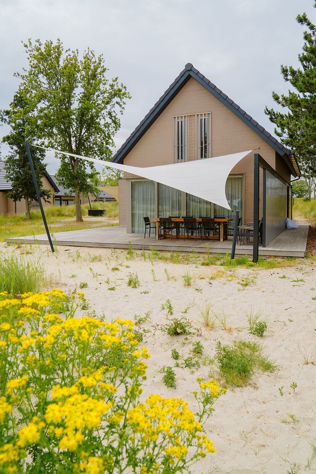 A modern house with a large patio, a dining area, and a covered outdoor space.
