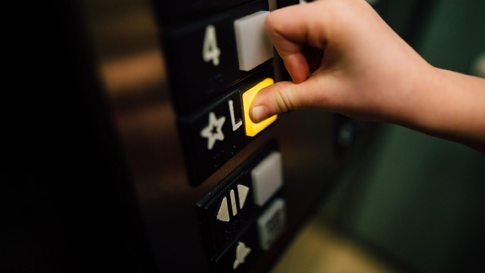 Una mano presionando un botón con un símbolo de estrella en un panel de control de ascensor.