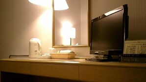 A hotel room with a bedside table, a lamp, a television, and a menu board. - OTA Daiichi Hotel (Ota)
