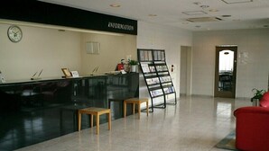A reception area with a black counter, a clock, and a magazine rack. - OTA Daiichi Hotel (Ota)