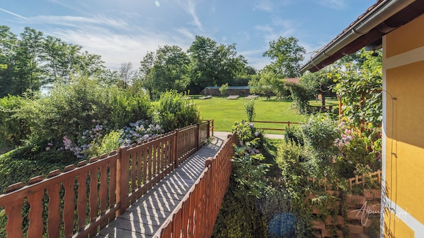 A wooden deck leading to a lush garden with a lawn and trees. - Panorama B&B (Ptuj)