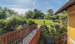 A wooden deck leading to a lush garden with a lawn and trees. - Panorama B&B (Ptuj)