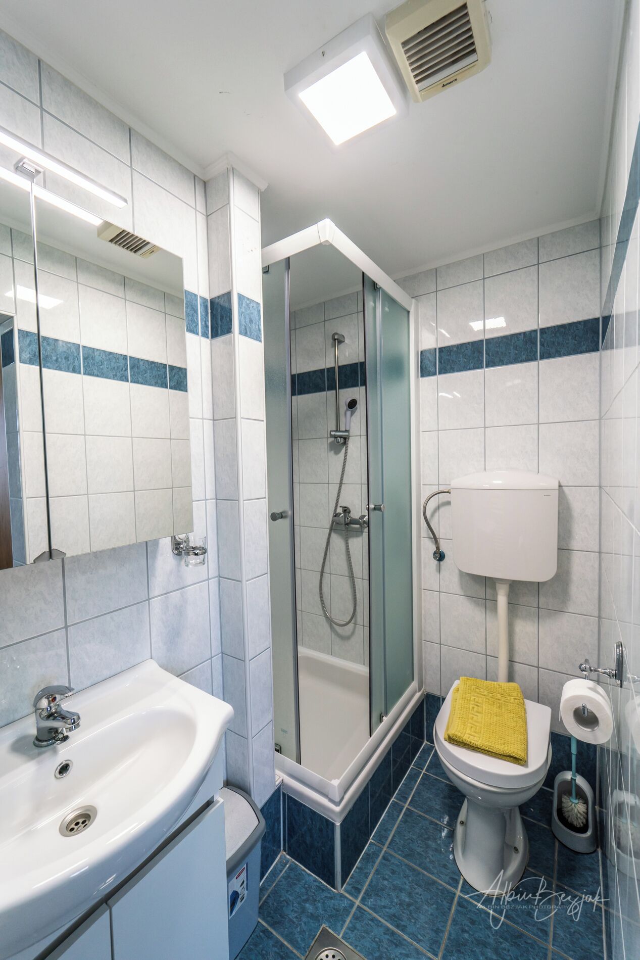 A modern bathroom with a glass-enclosed shower, a white sink, a toilet, and a bidet.
