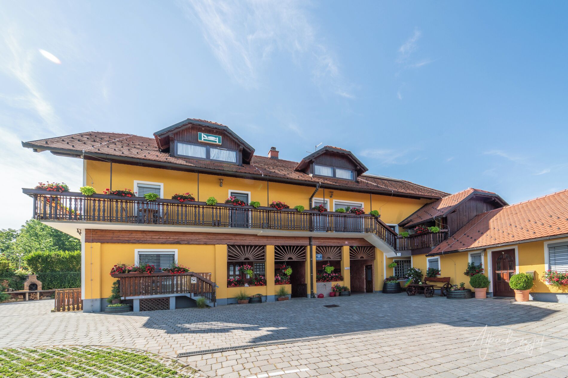 A two-story building with balconies, a covered entrance, and a paved courtyard.