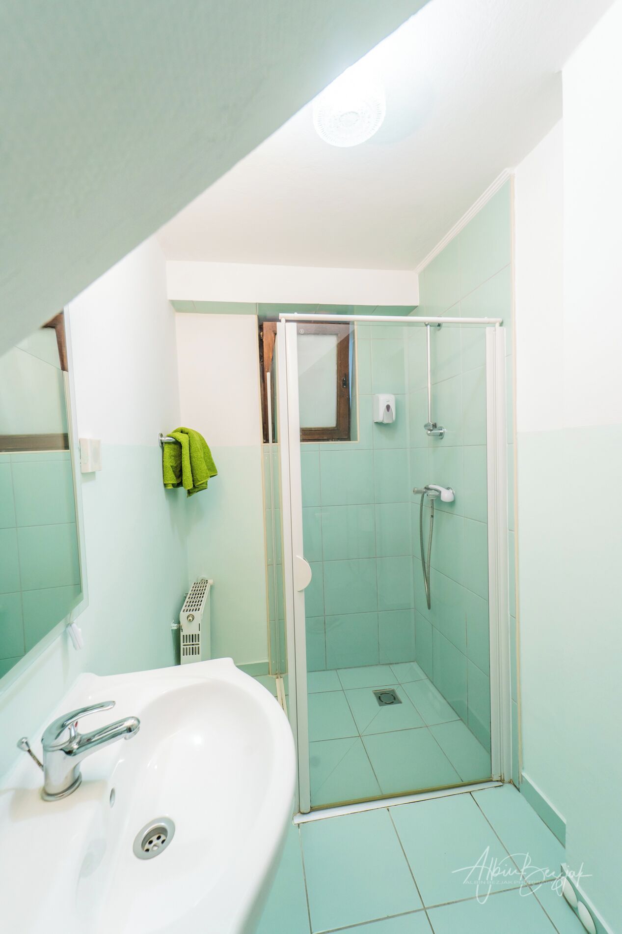 A bathroom with a glass-enclosed shower, a sink, and a mirror.