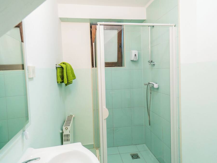 A bathroom with a glass-enclosed shower, a sink, and a mirror.