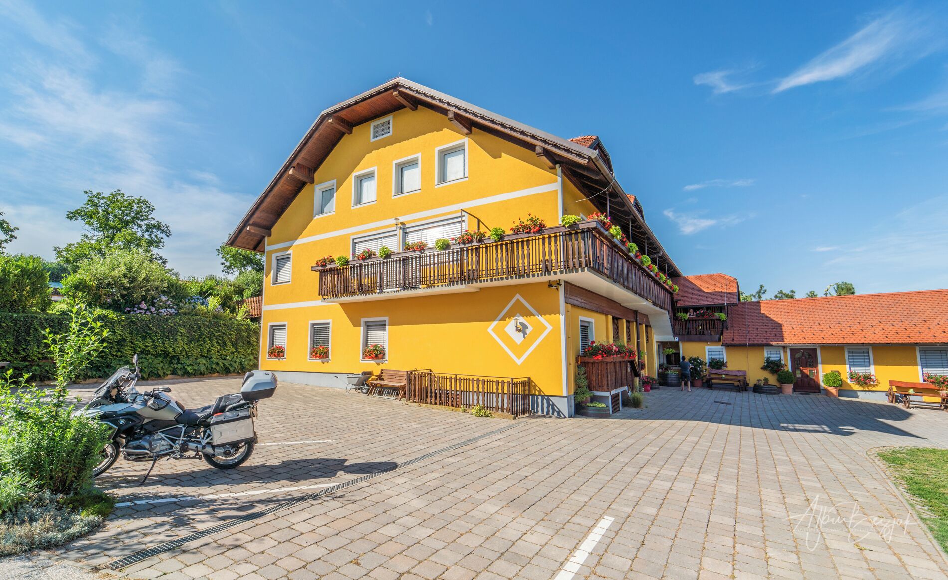 A yellow multi-story building with balconies, a paved driveway, and a parked motorcycle.