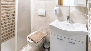 Un baño moderno con ducha, inodoro, lavamanos y armarios para almacenamiento.