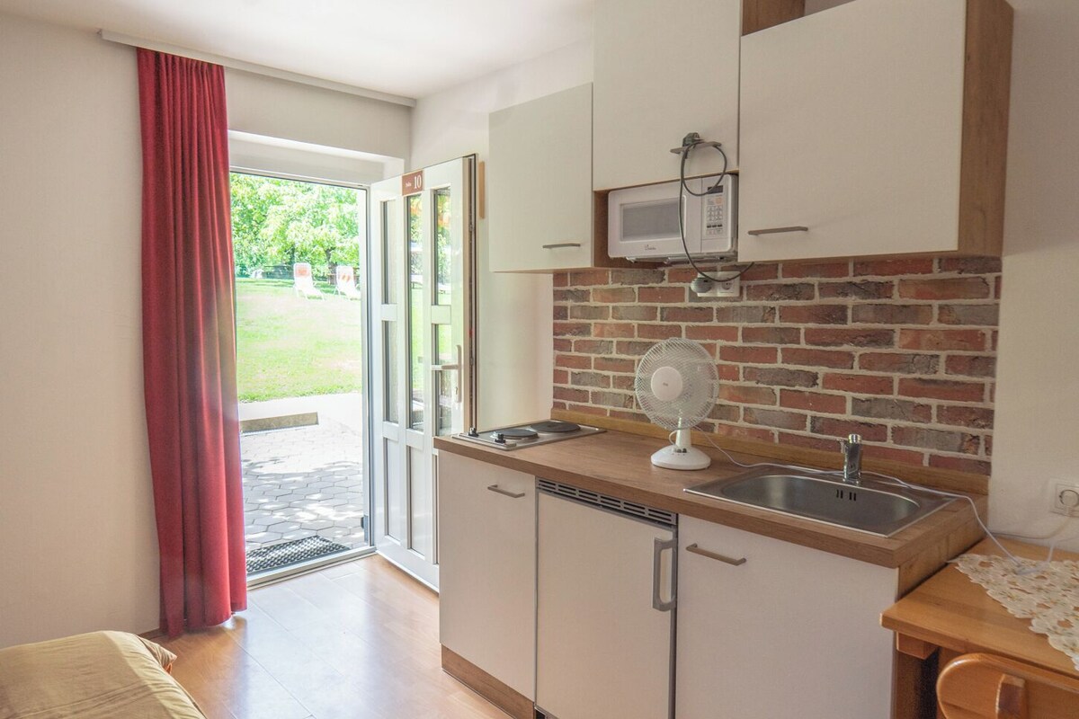 A compact kitchen with a microwave, a fan, and a sink.
