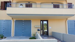 A multi-story building with a central entrance, balconies, and a gated driveway. - Casa Grongo (Alghero)
