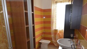A bathroom with a glass shower enclosure, a toilet, and a sink. - Casa Murena (Alghero)