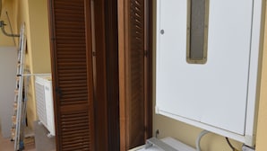 A narrow hallway with a white radiator, a wooden door, and a white cabinet. - Casa Murena (Alghero)