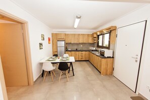 Compact kitchen area with dining table and refrigerator.