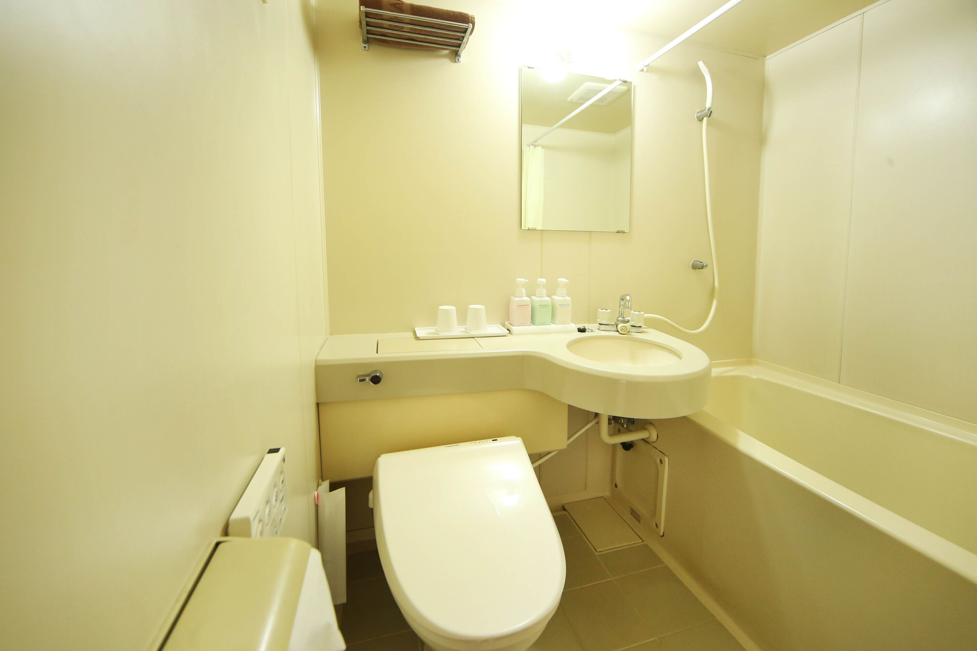 Un baño pequeño con inodoro, lavamanos y ducha.