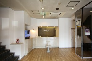 A reception area with a reception desk, a television, and a glass partition. - Harvest Hotel (Isesaki)