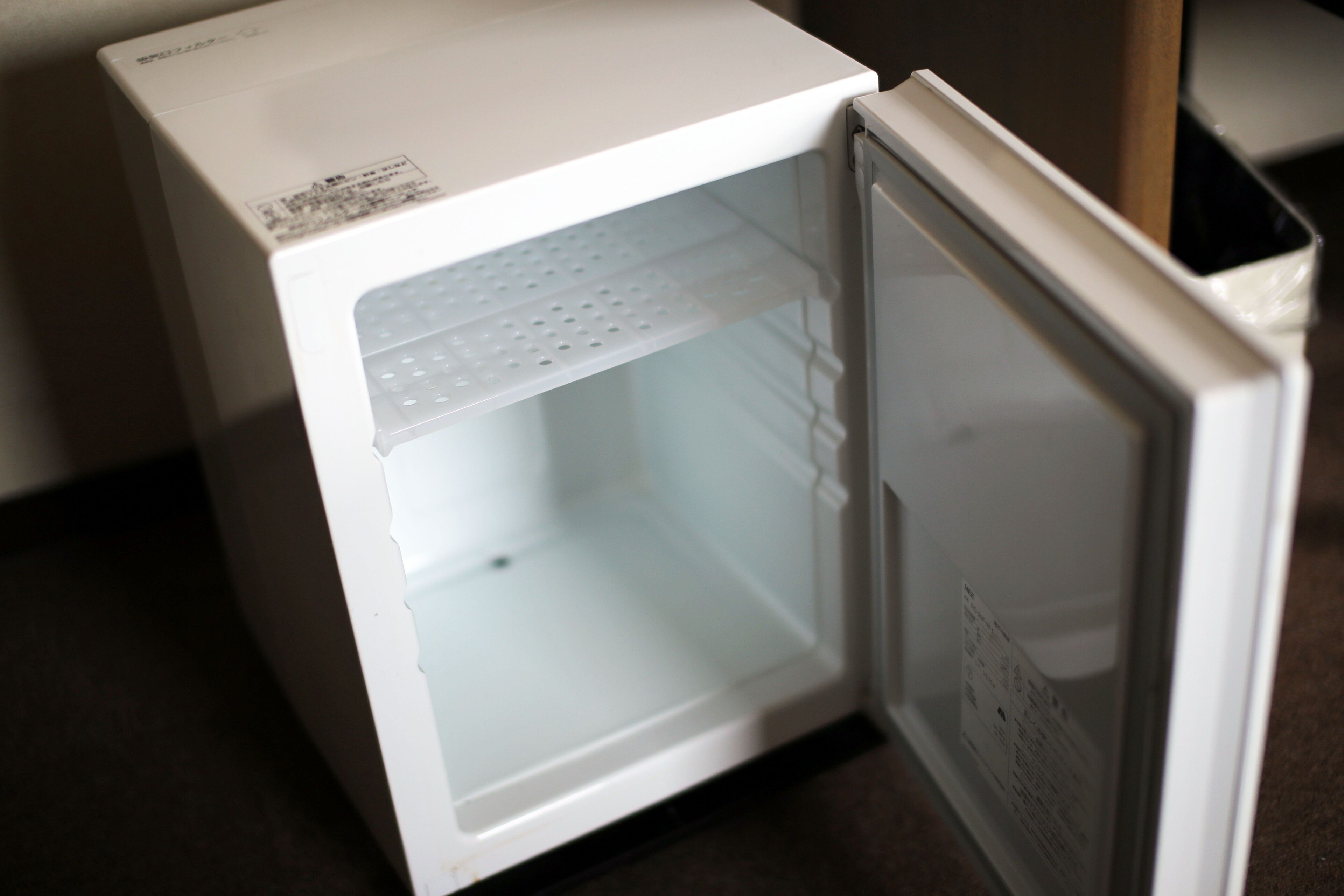 A white refrigerator with a glass door, a control panel on the top, and a small shelf inside.