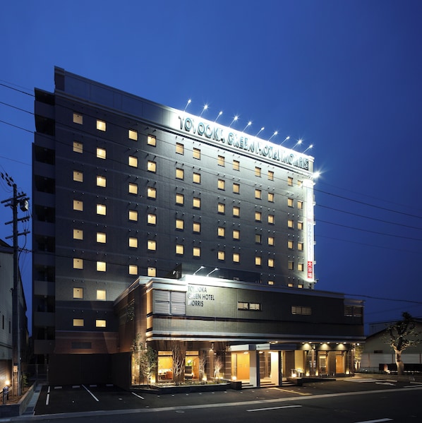 A multi-story hotel with a prominent sign, a ground-level entrance, and a parking lot.