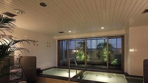 A modern bathroom with a glass-enclosed bathtub, a potted plant, and a view of the outdoors through a large window. - Toyooka Green Hotel Morris (Toyooka)