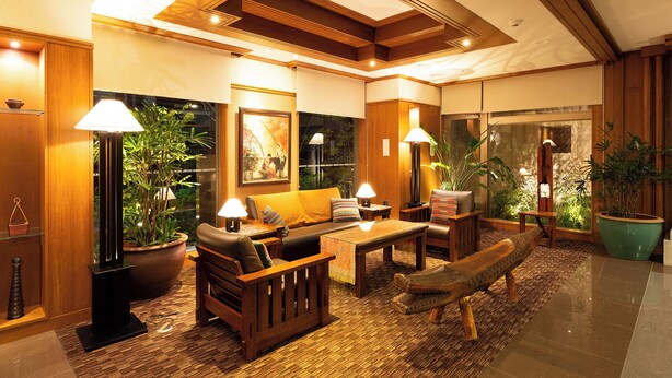 A modern living room with a sofa, coffee table, and lamps. There are potted plants and a large window. - Toyooka Green Hotel Morris (Toyooka)