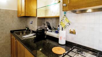 A kitchen with wooden cabinets, a stainless steel sink, a gas stove, and a countertop with various kitchen items.