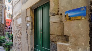 Un edificio de piedra con una puerta verde, un escalón exterior pequeño y un cartel con un código QR.