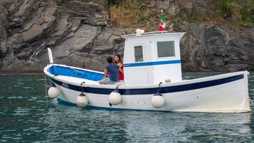 Una pequeña embarcación con dos personas a bordo, anclada cerca de acantilados rocosos.