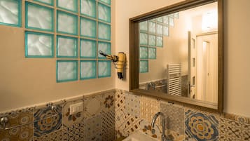 Een badkamer met een wastafel, spiegel en een aan de muur bevestigde haardroger.
