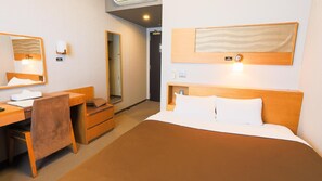 A hotel room with a bed, a desk with a chair, a mirror, and a wall-mounted light fixture. - Castle Inn Sendai (Sendai)