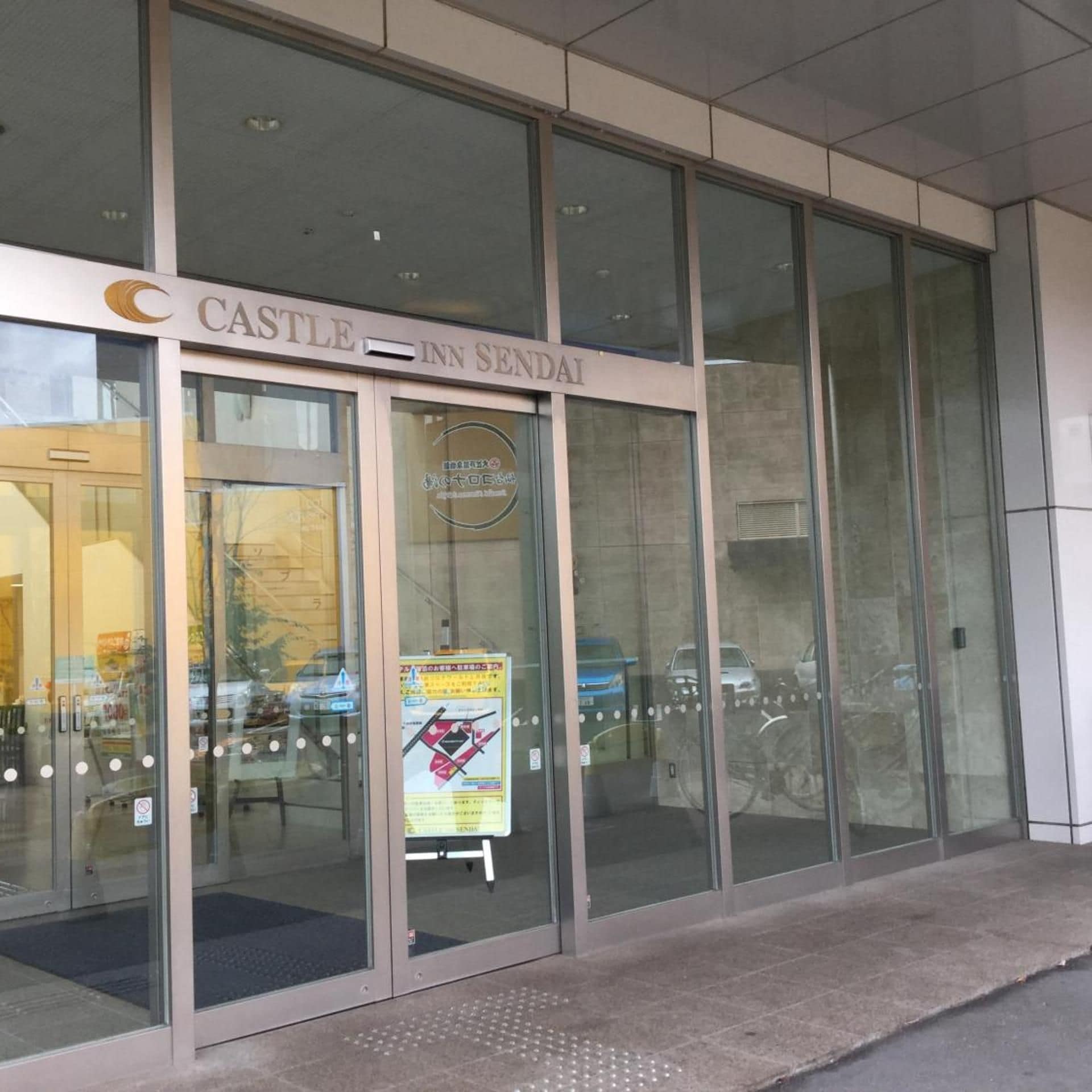 The entrance to Castle Inn Sendai with large glass doors and a visible sign.