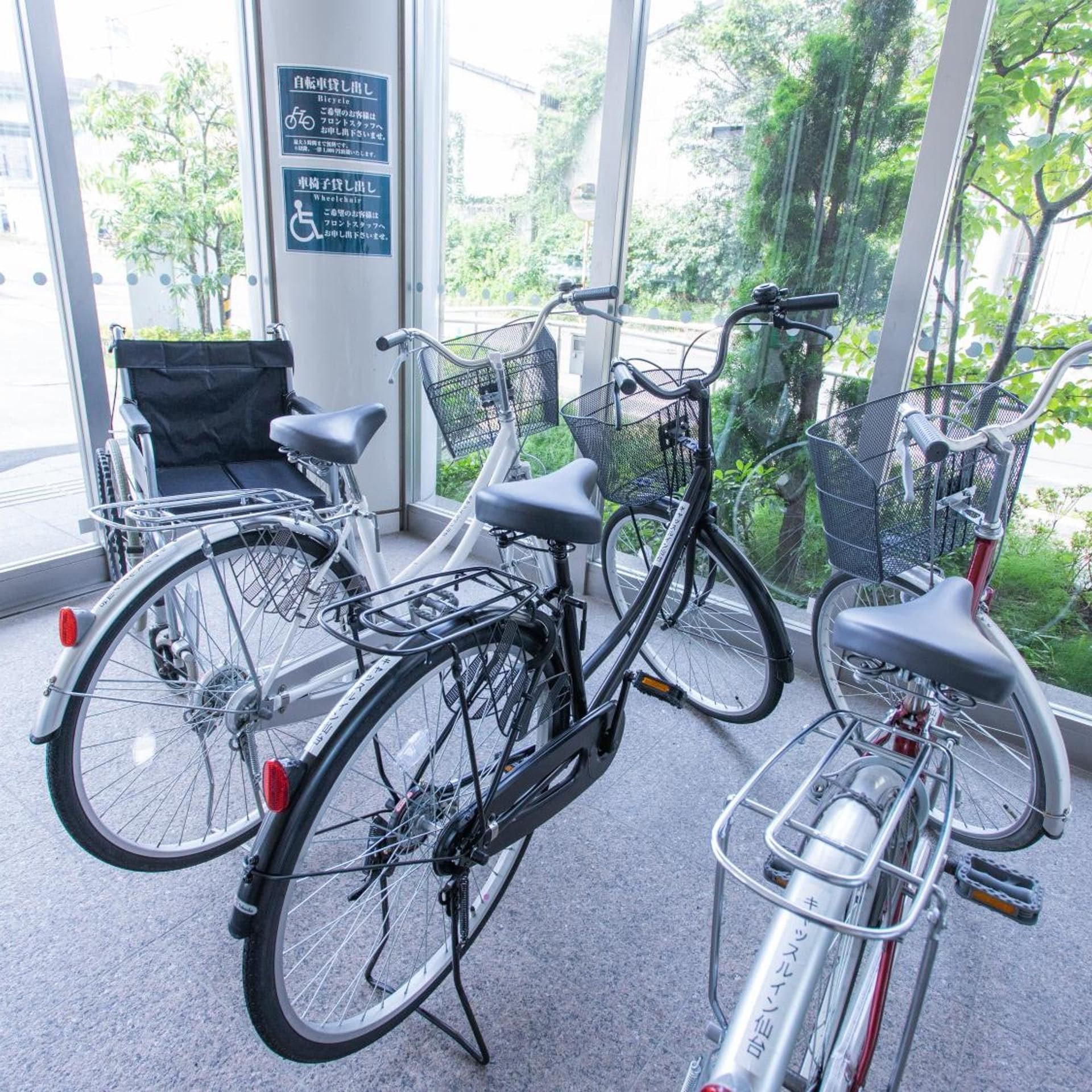 Bicicletas estacionadas dentro de um edifício com grandes janelas.