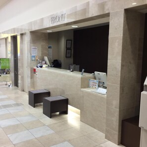 A reception area with a marble counter, a sign reading 'FRONT', and a small seating area with two stools. - Castle Inn Sendai (Sendai)