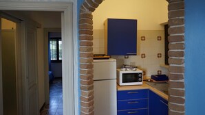 A kitchen with blue cabinets, a white refrigerator, and a microwave. - Casa Ostrica (Alghero)