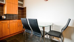 A kitchen with wooden cabinets, a glass table, and two black chairs. - Beach Boulevard Apartment (Aberdeen)