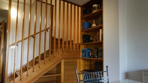 Una escalera de madera con una mesa y sillas de vidrio en una habitación con estanterías.