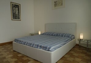 A bedroom with a large bed, two bedside tables, and wall art.