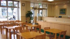 A restaurant with wooden tables and chairs, a counter with a display, and a view of the street outside. - HOTEL CROWN HILLS TSUCHIURAEKIHIGASHI (Tsuchiura)