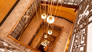 Vista de una escalera con barandillas de metal ornamentadas y lámparas colgantes.