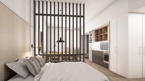 Un dormitorio moderno con una cama grande, un separador de madera y una kitchenette.